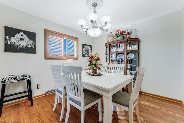 dining area with light hardwood / wood-style floors and a notable chandelier