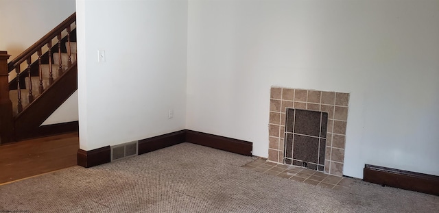 carpeted empty room with a fireplace