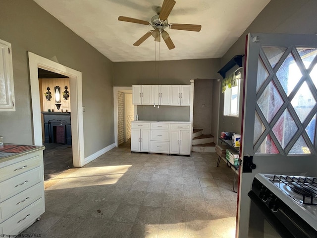 kitchen featuring white cabinetry, ceiling fan, and white gas stove