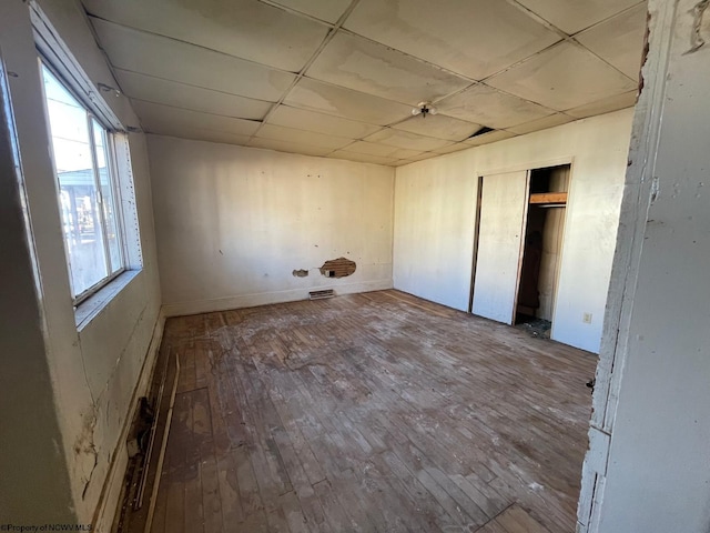 unfurnished bedroom featuring a closet, wood-type flooring, and a paneled ceiling