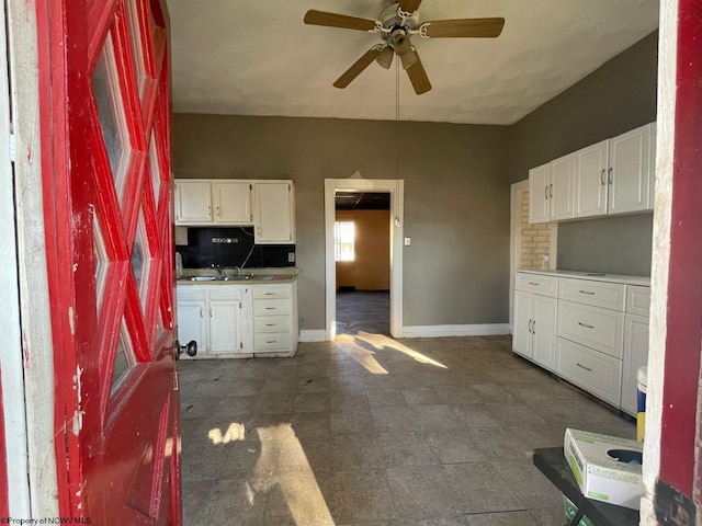 kitchen with backsplash, white cabinetry, sink, and ceiling fan