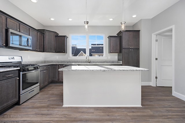 kitchen featuring dark brown cabinetry, a center island, dark wood-type flooring, hanging light fixtures, and appliances with stainless steel finishes