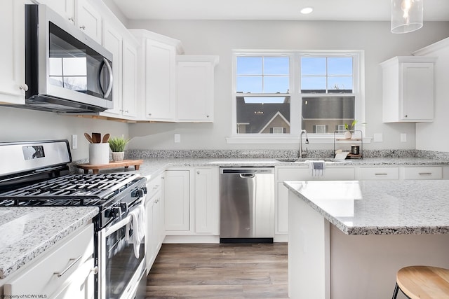 kitchen featuring a kitchen bar, stainless steel appliances, white cabinetry, and hardwood / wood-style flooring