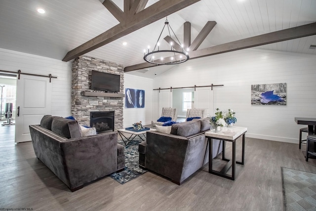 living room with beamed ceiling, wood-type flooring, a barn door, and a healthy amount of sunlight