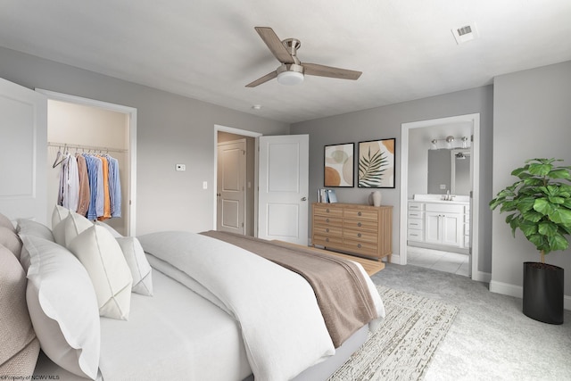 carpeted bedroom with a walk in closet, ensuite bath, ceiling fan, sink, and a closet