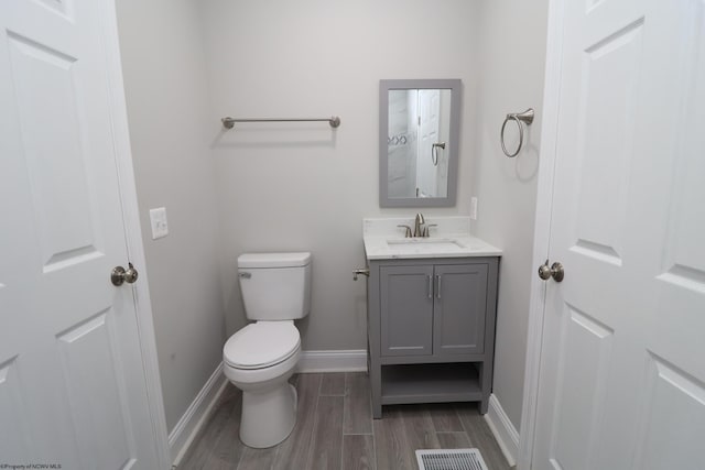 bathroom with hardwood / wood-style floors, vanity, and toilet