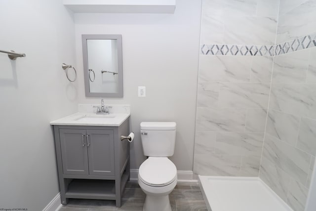 bathroom with tiled shower, vanity, and toilet