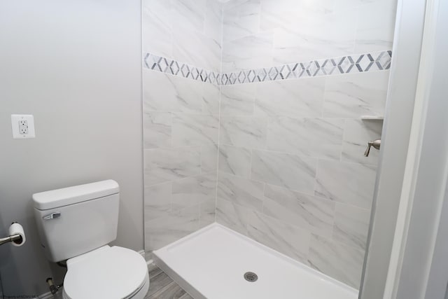 bathroom with a tile shower and toilet