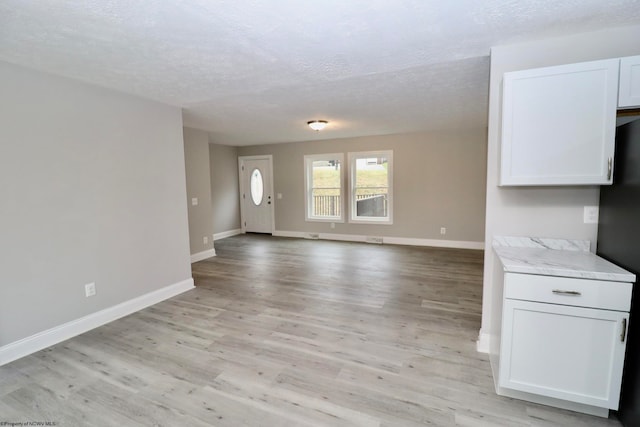 unfurnished living room with light hardwood / wood-style floors and a textured ceiling