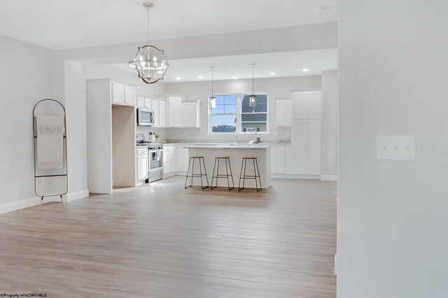 kitchen featuring stainless steel appliances, a kitchen island, decorative light fixtures, a breakfast bar area, and white cabinets