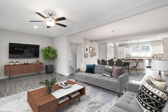 living room with ceiling fan with notable chandelier and hardwood / wood-style flooring