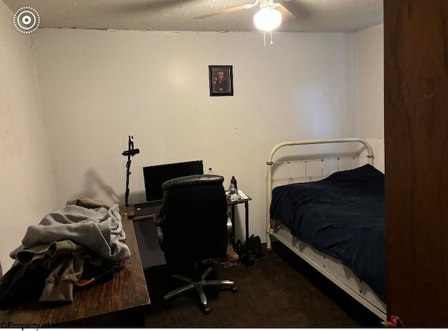 bedroom with ceiling fan, dark carpet, and a textured ceiling