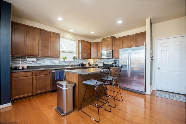 kitchen featuring sink, stainless steel appliances, a kitchen island, and light hardwood / wood-style flooring