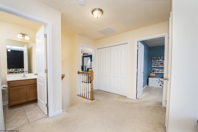 hall with light colored carpet and sink