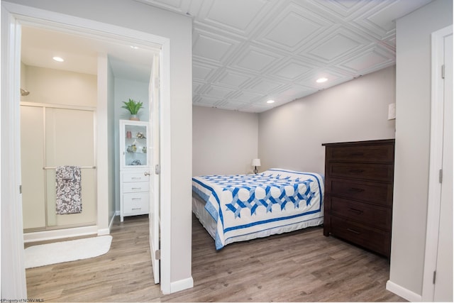 bedroom with ensuite bath and hardwood / wood-style flooring