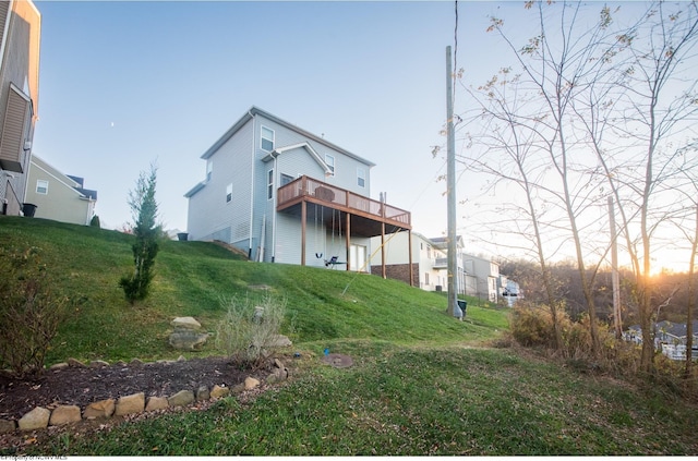 back house at dusk featuring a yard and a balcony