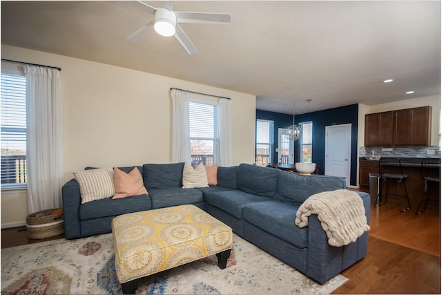 living room featuring hardwood / wood-style floors, a healthy amount of sunlight, and ceiling fan with notable chandelier