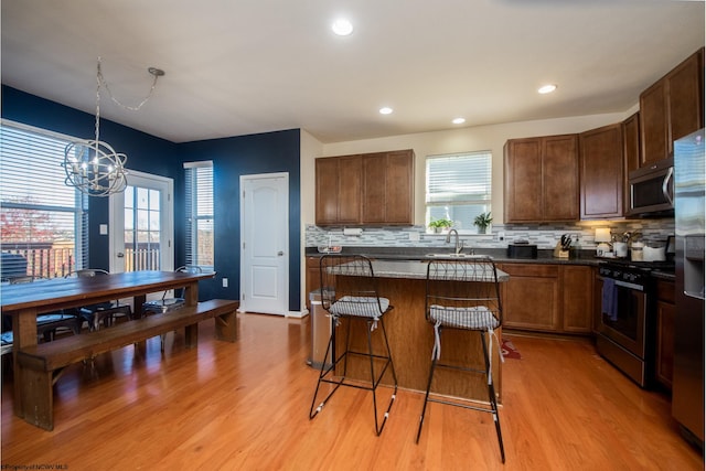 kitchen featuring a center island, stainless steel appliances, light hardwood / wood-style flooring, decorative light fixtures, and decorative backsplash