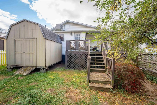 back of house with a storage unit, a yard, and a wooden deck