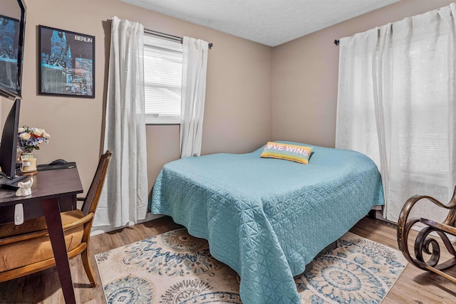 bedroom with a textured ceiling and light hardwood / wood-style flooring