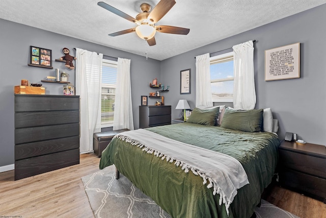 bedroom featuring a textured ceiling, light wood-type flooring, and ceiling fan