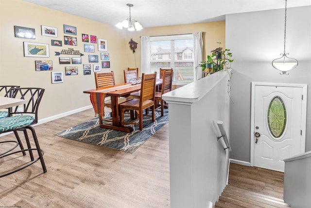 dining space with light hardwood / wood-style flooring and a notable chandelier