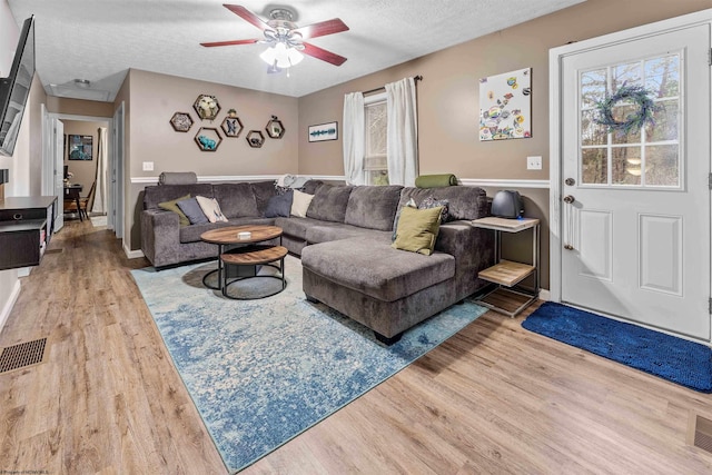 living room featuring a textured ceiling, hardwood / wood-style flooring, and ceiling fan