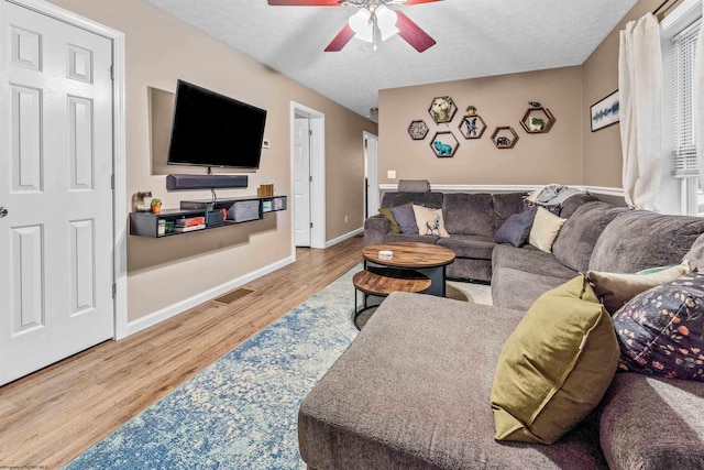 living room with ceiling fan, a textured ceiling, and hardwood / wood-style flooring