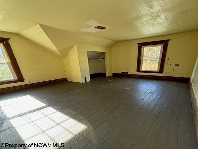 bonus room with a wealth of natural light, dark wood-type flooring, and vaulted ceiling