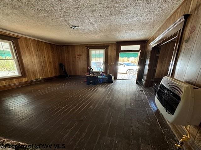 misc room featuring heating unit, dark hardwood / wood-style floors, plenty of natural light, and wood walls