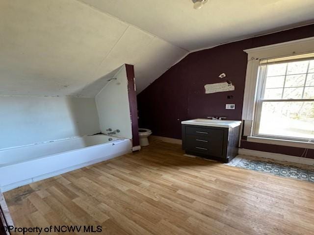 bathroom with a washtub, vanity, hardwood / wood-style flooring, and lofted ceiling