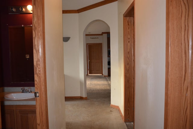 hall featuring crown molding, sink, and light tile patterned floors