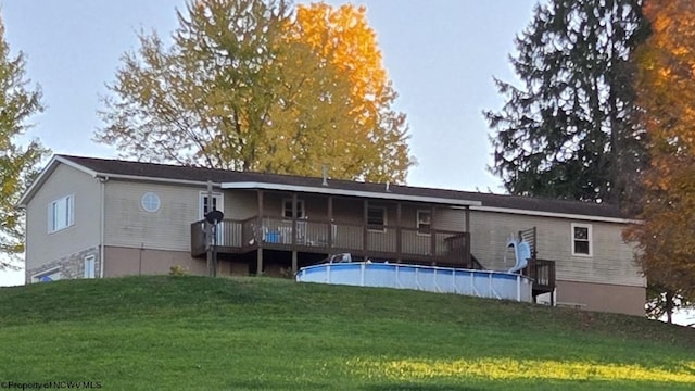 back of house featuring a lawn and a swimming pool side deck