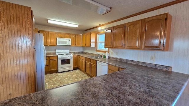 kitchen featuring kitchen peninsula, a textured ceiling, white appliances, wooden walls, and sink