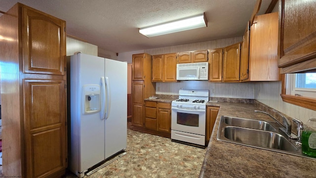 kitchen featuring a textured ceiling, white appliances, and sink