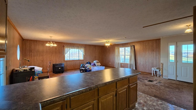 kitchen featuring carpet flooring, ceiling fan with notable chandelier, a textured ceiling, and hanging light fixtures