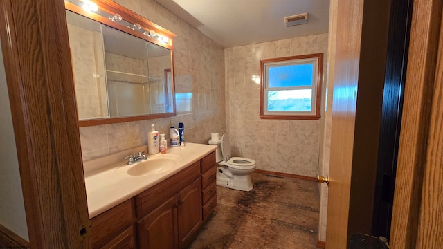 bathroom featuring tasteful backsplash, a tile shower, vanity, tile walls, and toilet