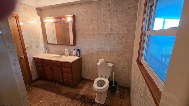 bathroom with vanity, toilet, and tile walls