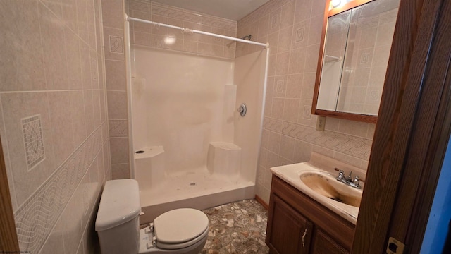 bathroom featuring a shower, toilet, decorative backsplash, vanity, and tile walls