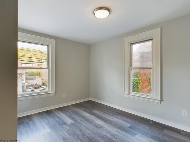 spare room featuring a healthy amount of sunlight and dark hardwood / wood-style flooring