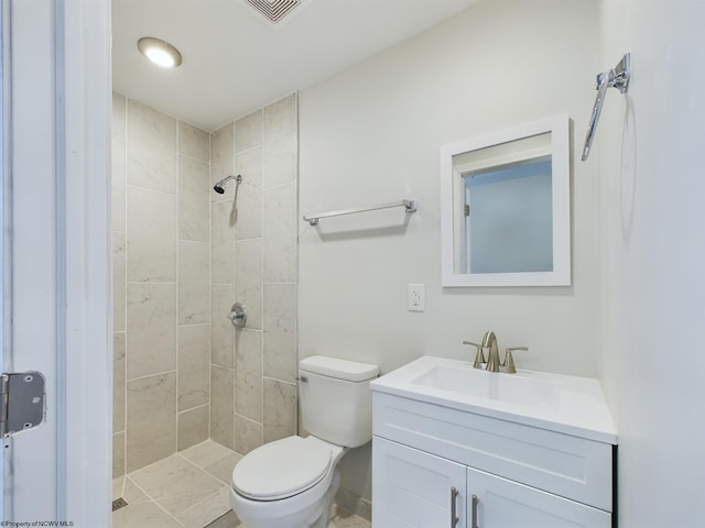 bathroom with vanity, toilet, and tiled shower