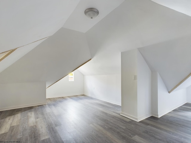 additional living space with dark wood-type flooring and lofted ceiling