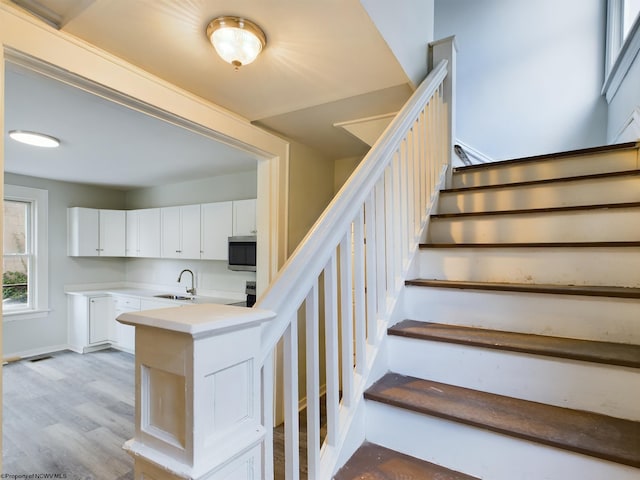 staircase featuring hardwood / wood-style floors and sink