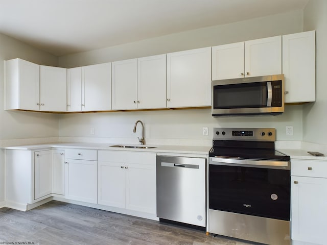 kitchen featuring appliances with stainless steel finishes, light wood-type flooring, white cabinetry, and sink