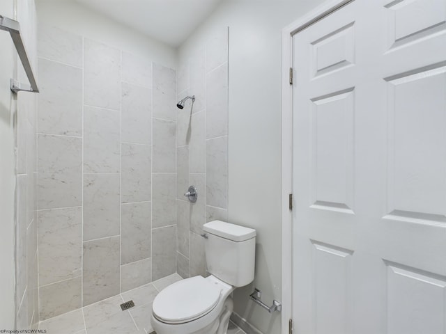 bathroom with a tile shower and toilet