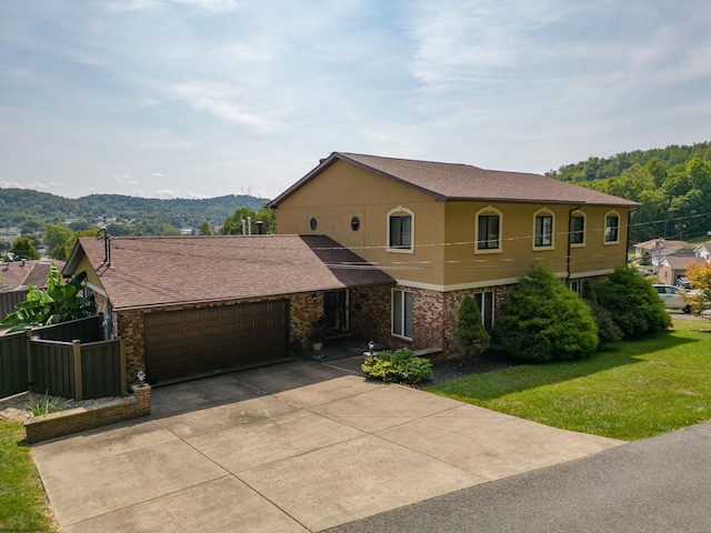 view of front of house featuring a mountain view, a front yard, and a garage