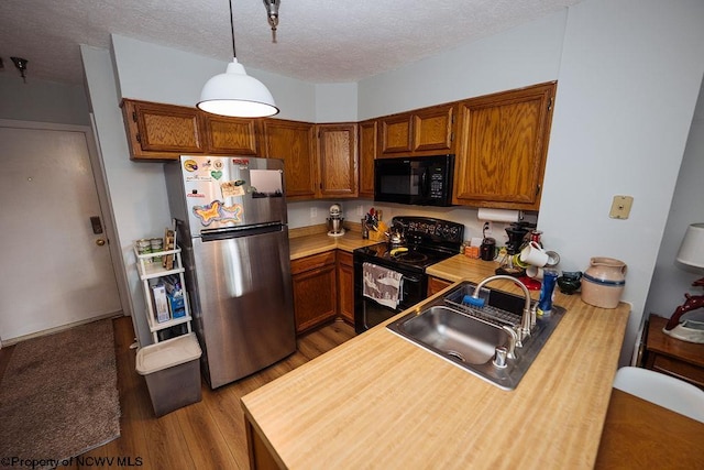 kitchen with sink, hanging light fixtures, hardwood / wood-style floors, a textured ceiling, and black appliances