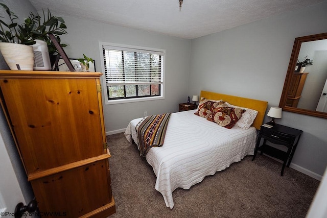 bedroom with a textured ceiling and dark carpet