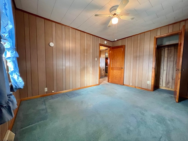 unfurnished bedroom with carpet floors, ceiling fan, crown molding, and wood walls