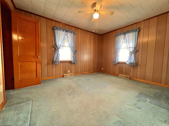 unfurnished room featuring ceiling fan, wooden walls, and carpet